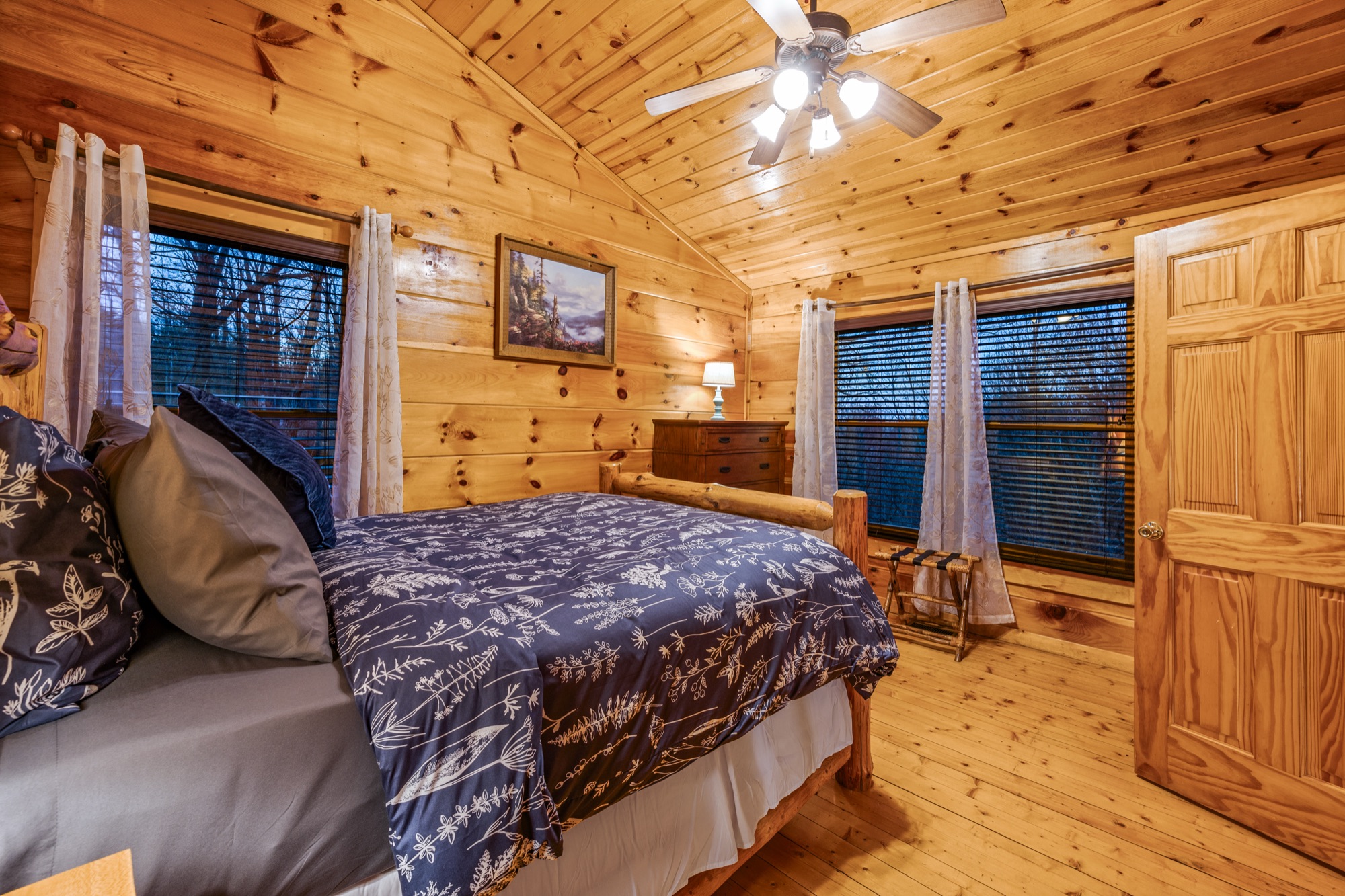 Loft bedroom at Bearadise with a ceiling fan, log dresser, and windows on two walls